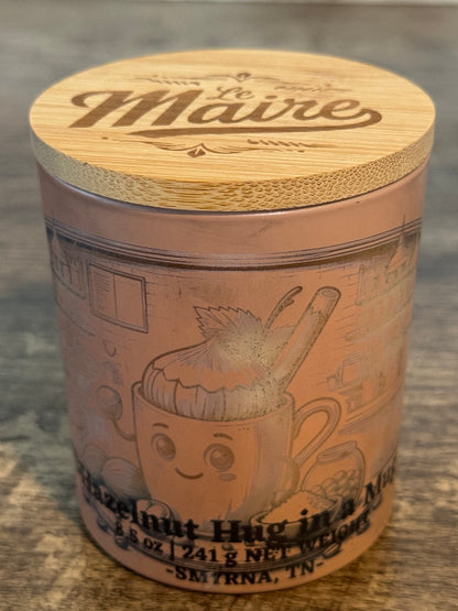 Hazelnut Hug in Mug soy candle angled view with yellow jar and engraved wood lid