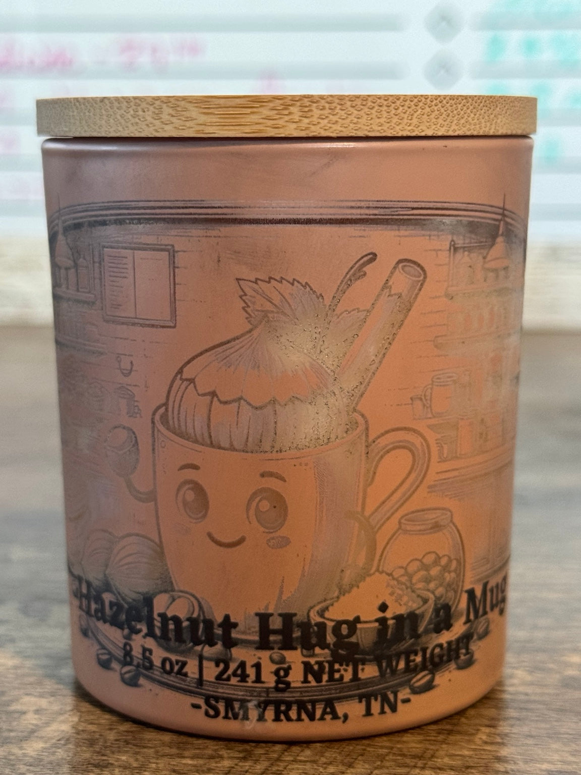Hazelnut Hug in Mug soy candle front view with yellow character jar and Le Maire wood lid