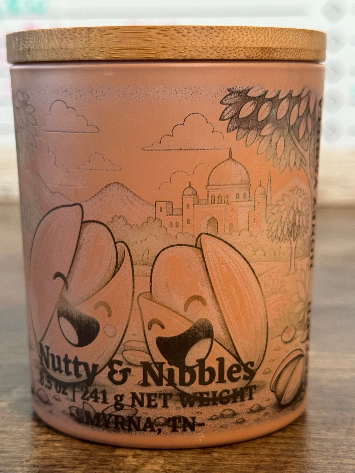 Nutty Nibbles pistachio vanilla soy candle front view with yellow character jar